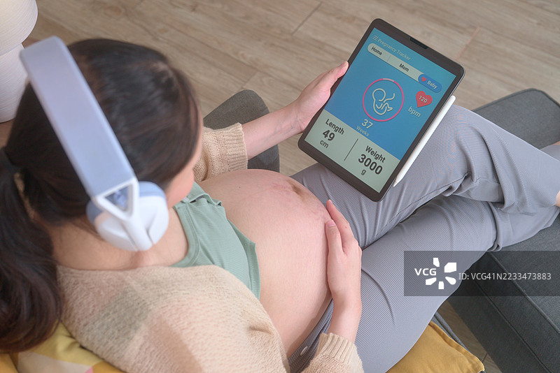 孕妇手中拿着显示怀孕追踪应用的平板电脑屏幕特写图片素材
