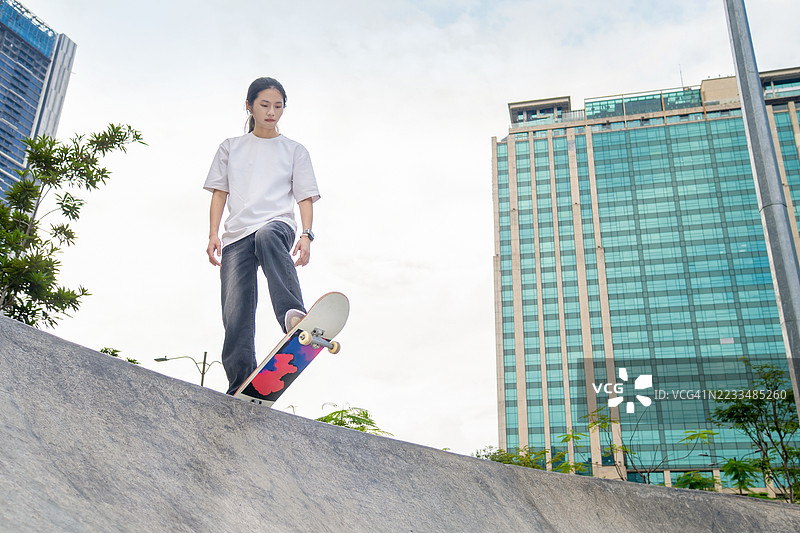 女孩在滑板坡道上玩滑板翻转动作图片素材
