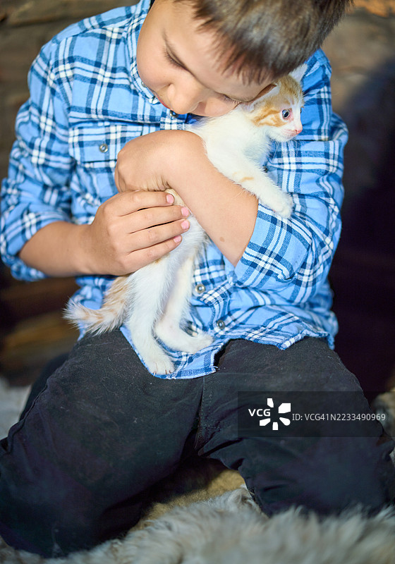 可爱男孩轻轻拥抱小红猫，把它贴在自己身上图片素材