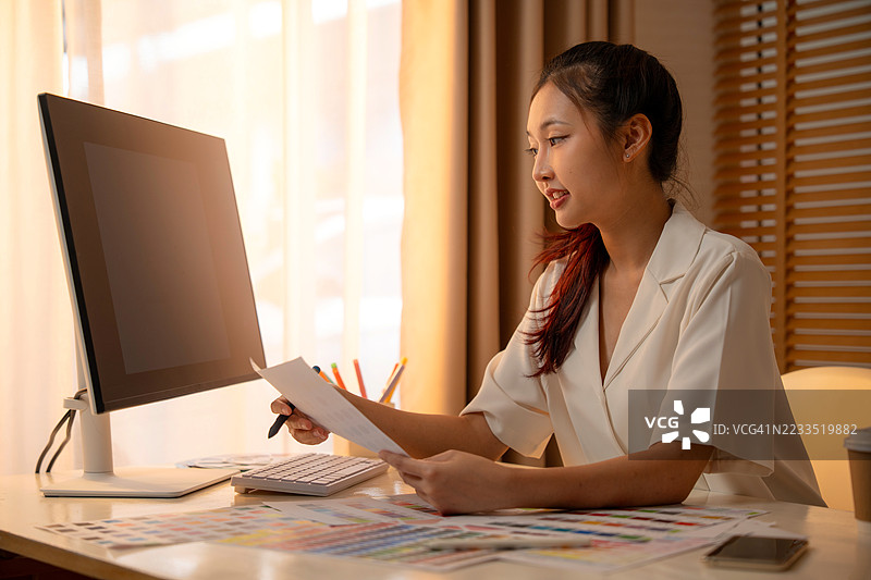 年轻的亚洲女性平面设计师在记录标志设计。色彩样本。艺术家在办公室的图形平板上绘制作品。平面设计师的创意编辑理念概念。图片素材