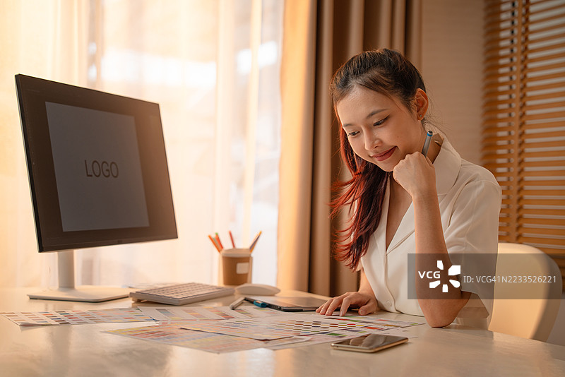 年轻的亚洲女性平面设计师在记录标志设计。色彩样本。艺术家在办公室的图形平板上绘制作品。平面设计师的创意编辑理念概念。图片素材