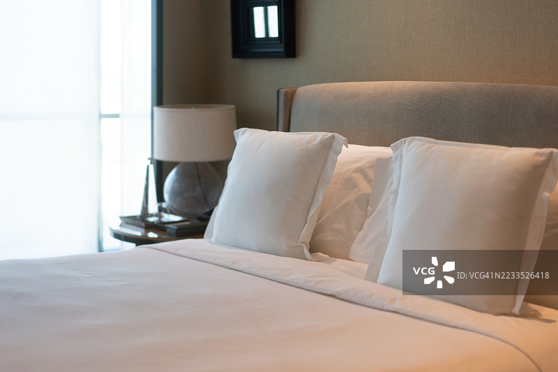 整洁的床铺，白色的枕头和房间里的床头灯图片素材