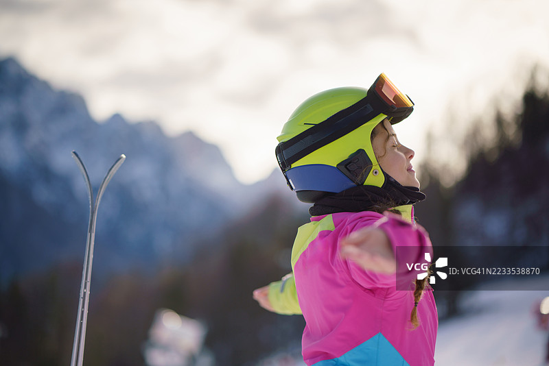 侧面视角的少女穿着滑雪服张开双臂图片素材