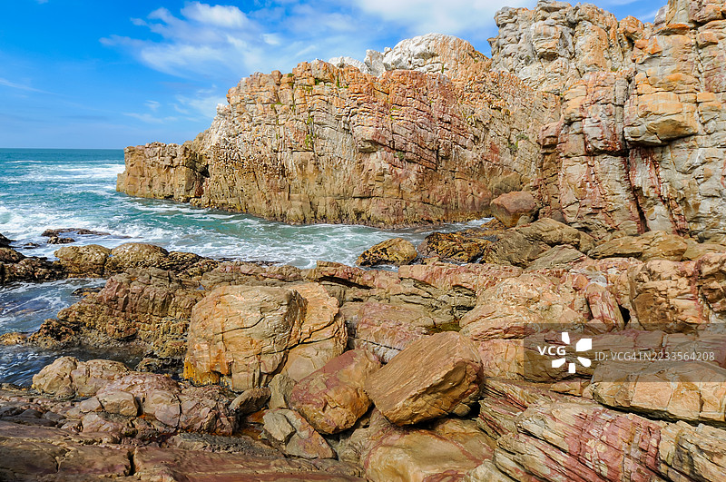 南非蓝天下的崎岖海岸岩石和海浪图片素材