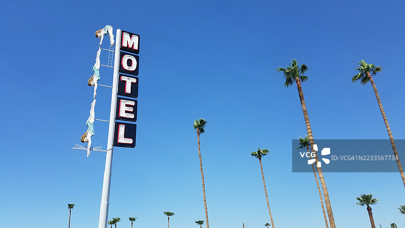 汽车旅馆招牌与棕榈树在晴朗的蓝天下图片素材