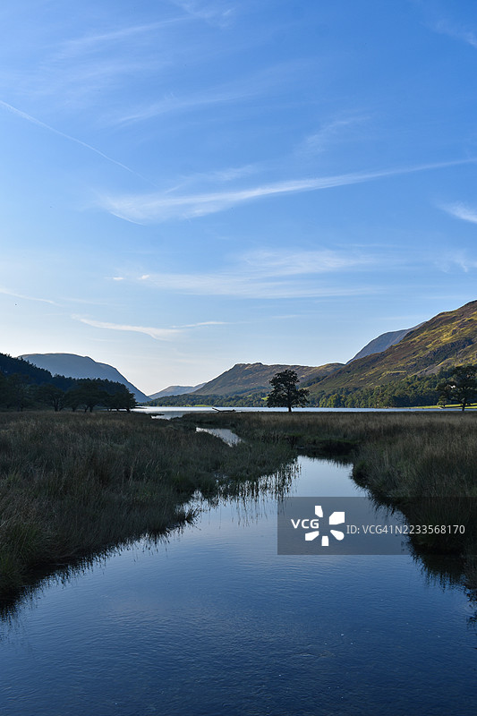 宁静的湖泊被群山环绕，蓝天清澈，位于英国科克默斯。图片素材