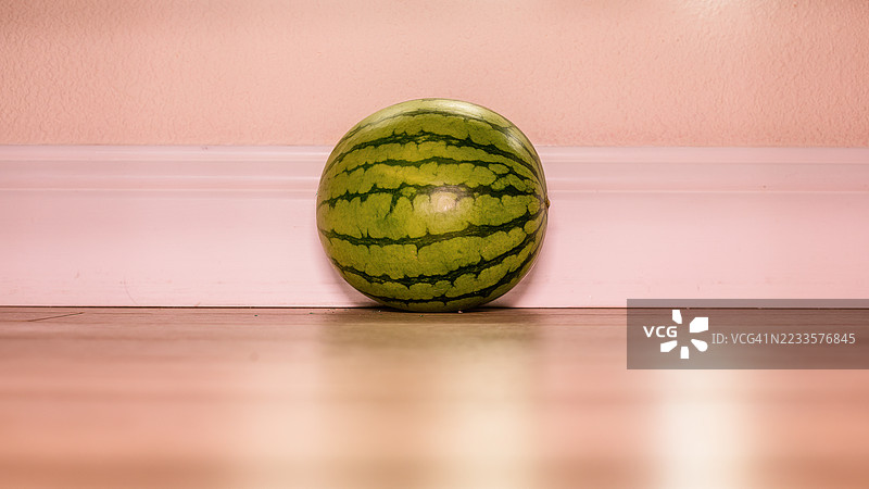 整颗西瓜靠在粉色墙壁上图片素材