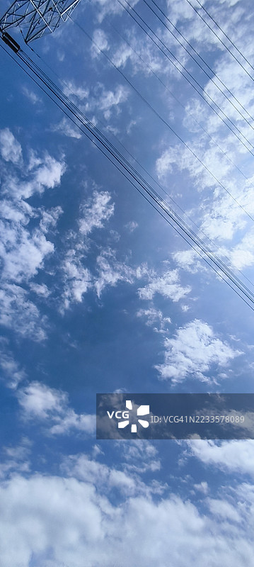 电力线在蓝天和零星云朵间延伸，印度尼西亚苏科曼农区图片素材