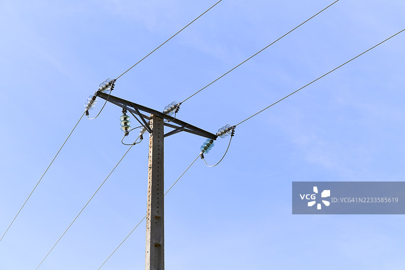 在蓝天背景下，混凝土电杆上供电的电力线图片素材