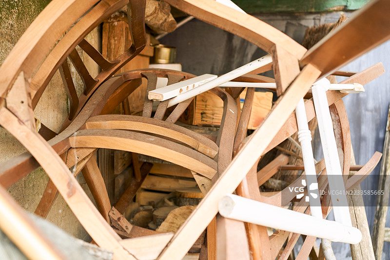 一堆被丢弃的木椅和家具零件积满灰尘图片素材