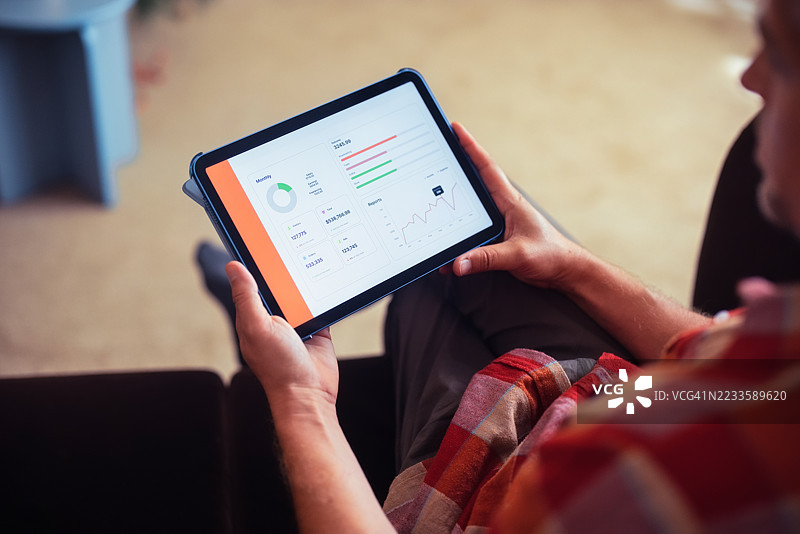 室内放松的人手持平板电脑查看商业报告图片素材
