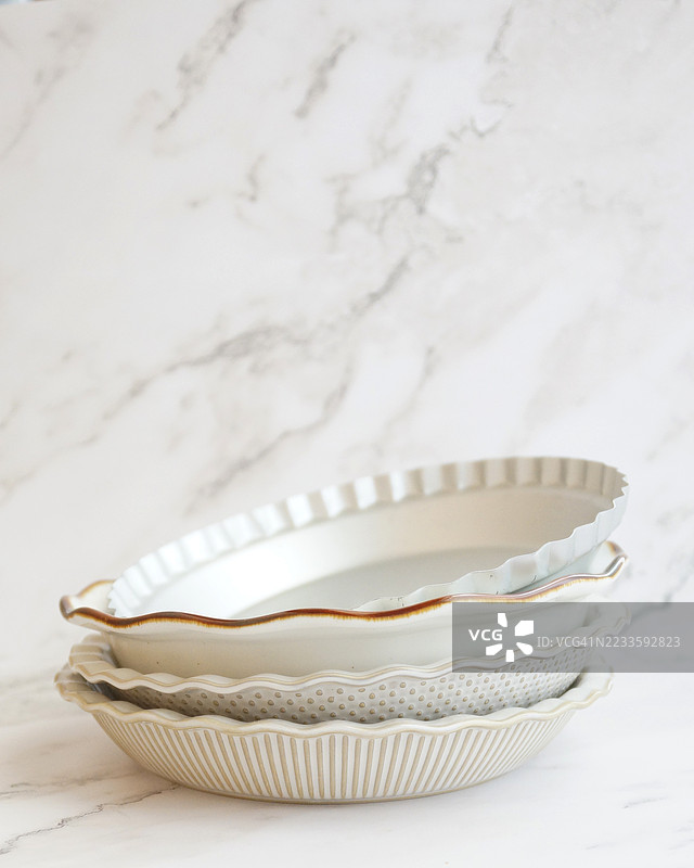 倾斜堆放的瓷器和复古金属派盘及锅具图片素材