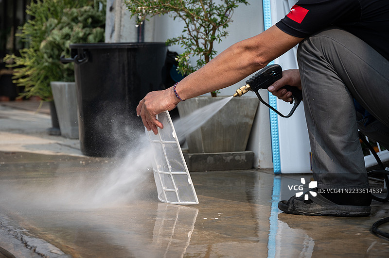 技术人员使用高压水枪清洗空调过滤器。图片素材