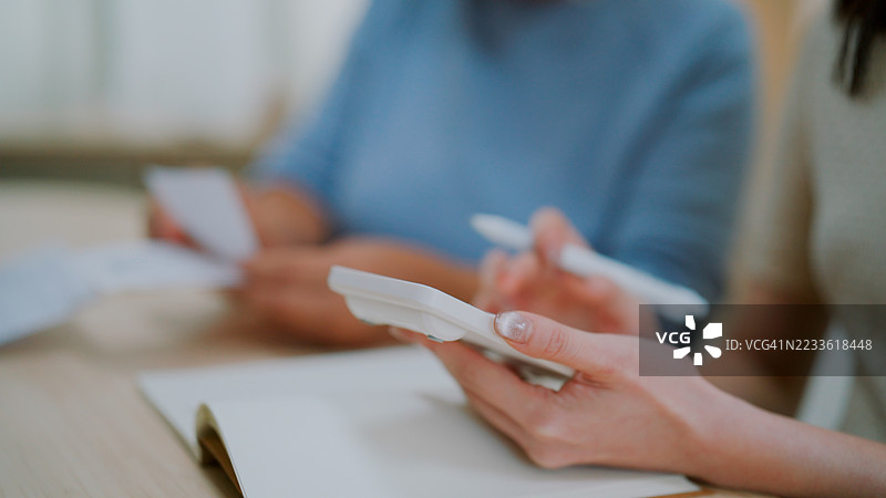 女人在帮助她的老母亲计算家庭开支。图片素材