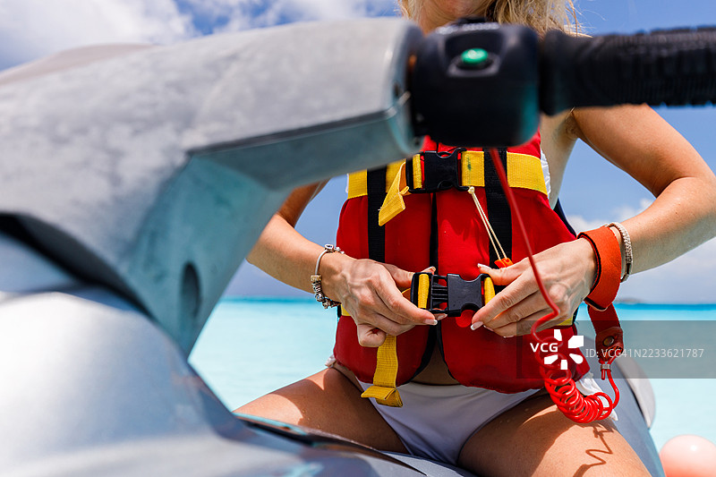 一名女性在海上骑乘喷气船前系安全带的特写镜头。图片素材