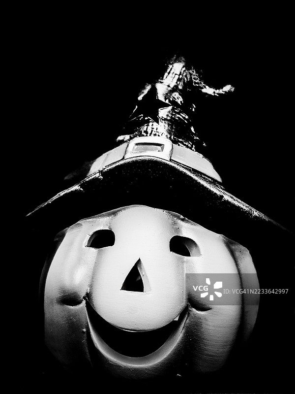 微笑的南瓜戴着女巫帽：黑白色调中的俏皮万圣节场景，节日的欢愉与阴森的阴影通过雕刻的表情、戏剧性的对比和奇幻的季节魔法相遇。图片素材