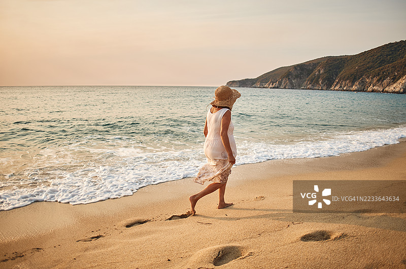 一位年长女性在海滩上悠闲地散步图片素材
