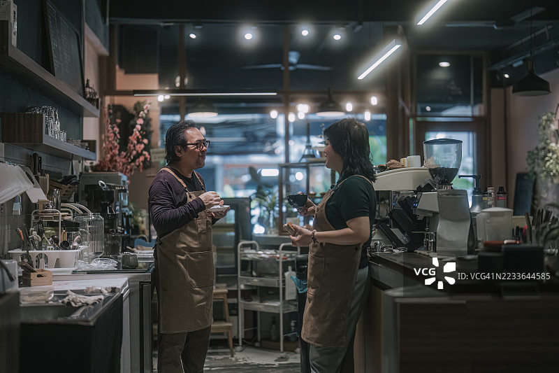 亚洲咖啡馆老板在柜台后休息喝咖啡图片素材