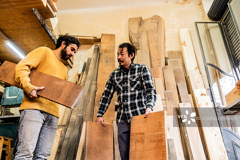 木匠在工作坊里一边整理木材一边交谈图片素材