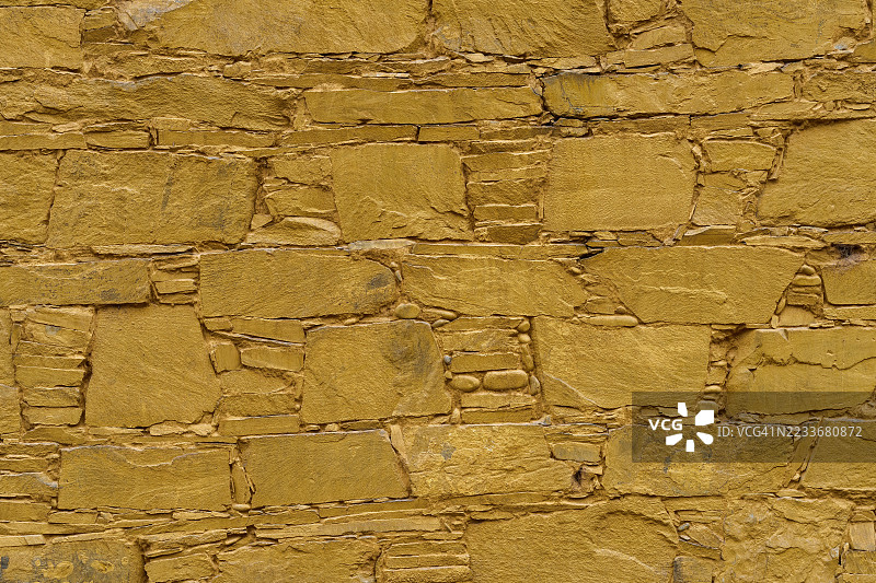 由大型劈石制成的浅色墙壁的纹理和背景。墙壁呈棕色。石头是矩形的，石头的风化程度各不相同。图片素材