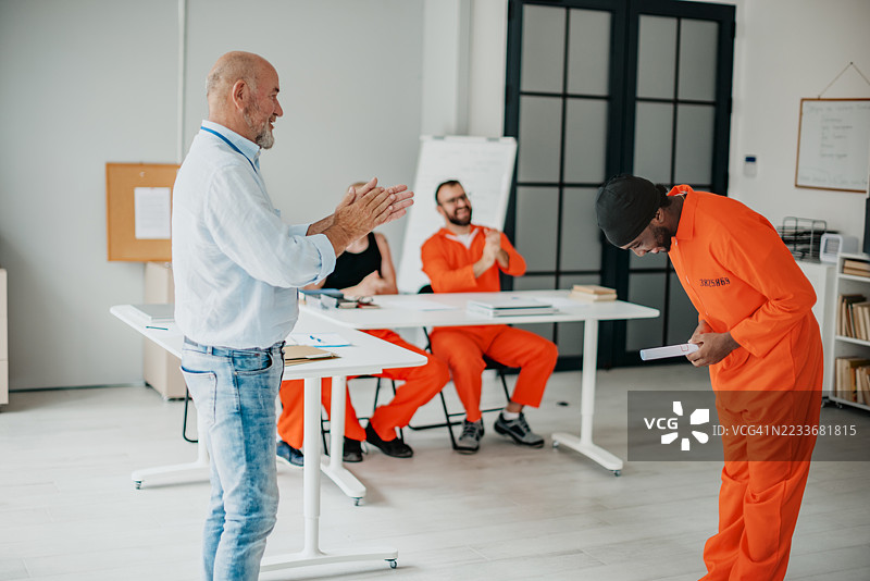 身穿橙色囚服的男性参与监狱教育项目，展现出团队合作和个人改造与成长的决心。图片素材