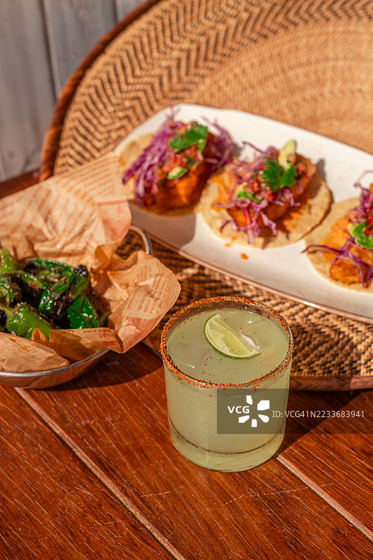 墨西哥虾海鲜塔可，配有玛格丽塔鸡尾酒、青柠、鳄梨酱、香菜和沙拉，在阳光明媚的图卢姆餐厅享用。图片素材