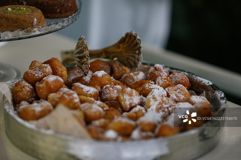 当地咖啡馆窗户里的新鲜烘焙迷你甜甜圈，撒上糖粉图片素材