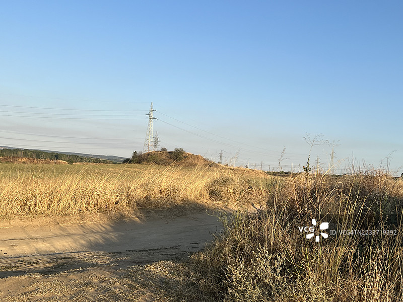 保加利亚的清澈天空下，干燥草地与电力线的乡村风景图片素材