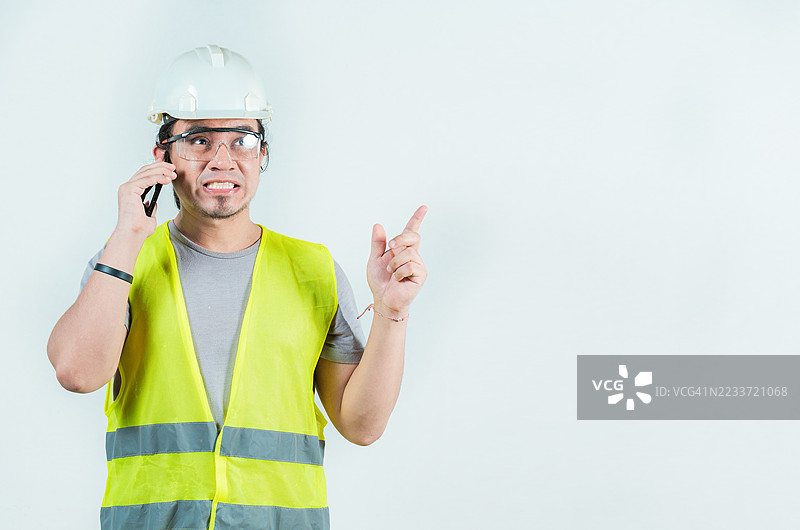身穿安全背心和头盔的工程师在白色背景前讲电话图片素材
