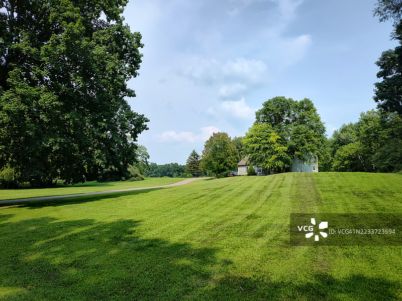 被郁郁葱葱的树木和草地环绕的房屋美景，蓝天之下，伊顿拉普兹，美国图片素材