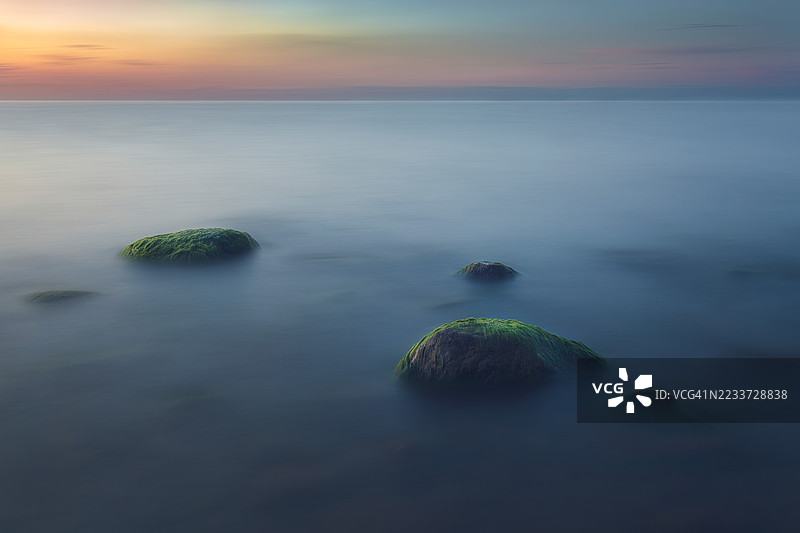 津巴布韦布拉瓦约，日落时宁静的海景与长满苔藓的岩石图片素材