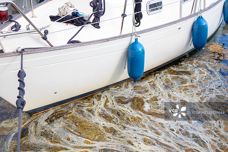 停泊在污染水域中的帆船特写图片素材
