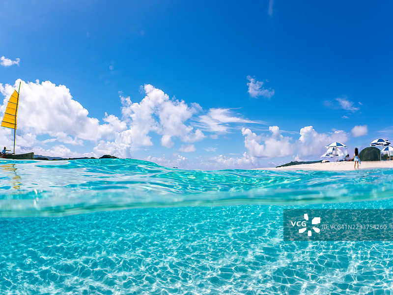 可以看到阳伞、船只，甚至是独特于冲绳的双体船Sabani。拍摄了美丽白沙滩的一半。还有一群热带鱼。美丽的珊瑚礁和游泳的人们。外岛、座间味岛、慶良間群岛。图片素材