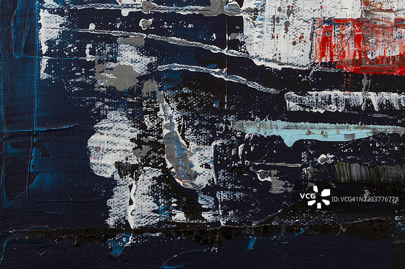 深蓝色背景下，彩色混乱的丙烯颜料的微距特写。图片素材