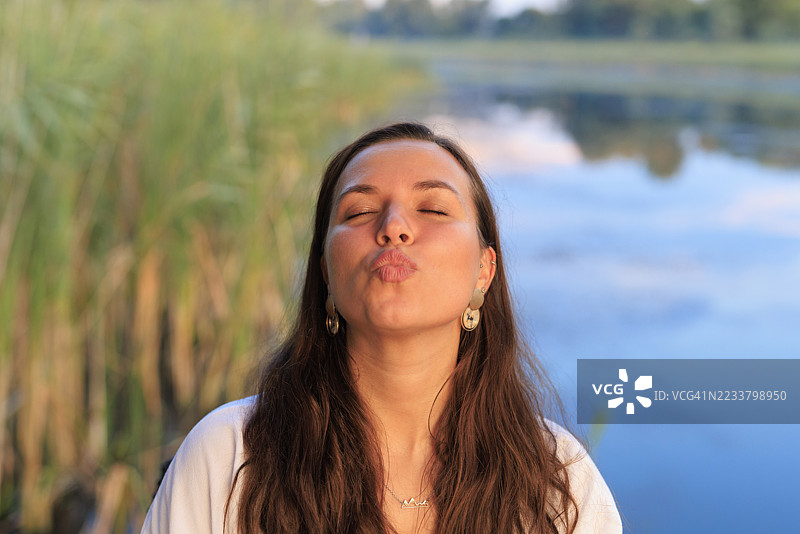 闭眼、嘴唇紧闭的女性肖像。湖边码头。生态旅游美丽的风景在水中倒影。图片素材