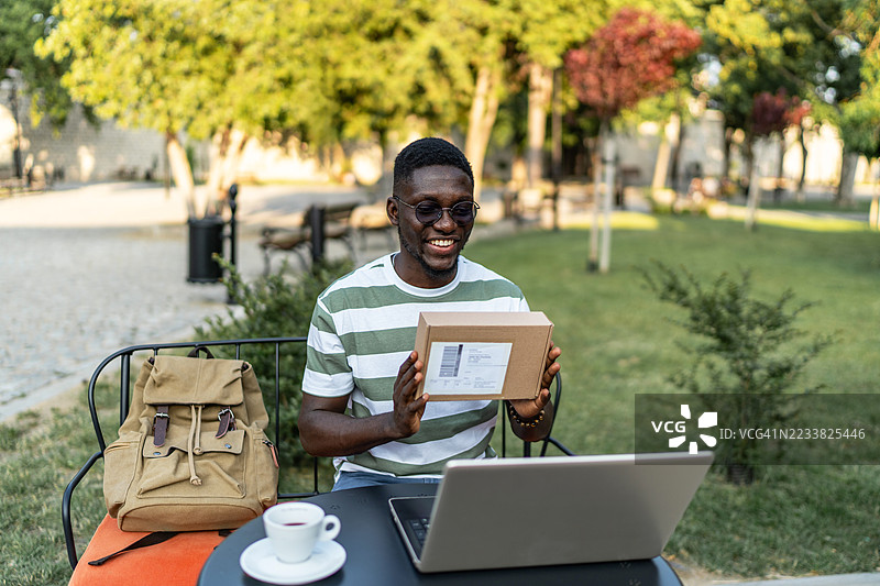 年轻男子在公园里的视频通话中展示包裹图片素材