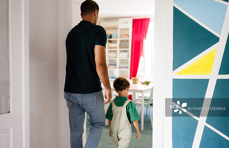 男看护人走进幼儿园的房间，里面有个小男孩图片素材