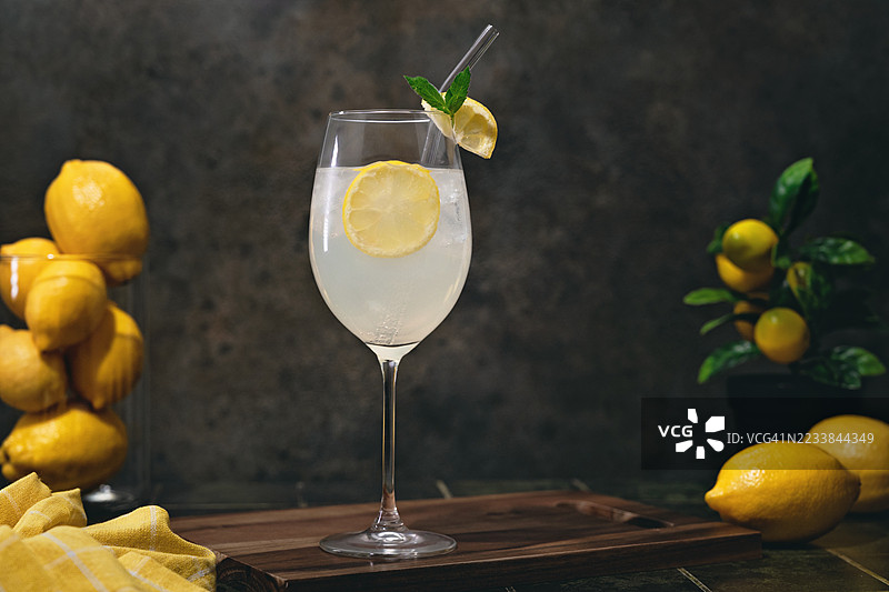 桌子上的柠檬酒气泡鸡尾酒，旁边有柠檬，留白空间。地中海花园氛围与休戚夏季鸡尾酒。图片素材