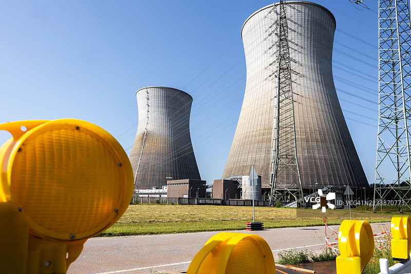核电站的两个巨型冷却塔位于道路障碍的黄色警示灯后面图片素材