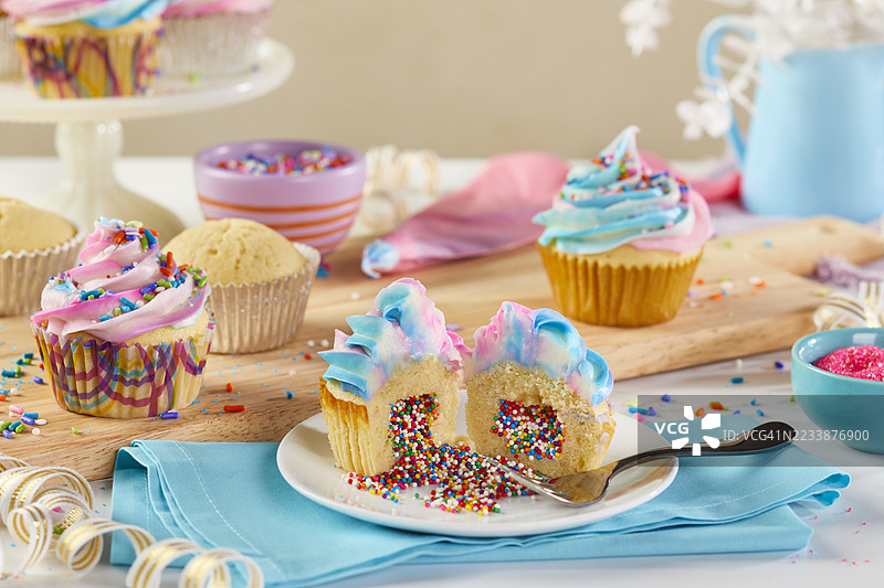 彩色独角兽杯子蛋糕正在装饰，其中一个已经被打开。图片素材