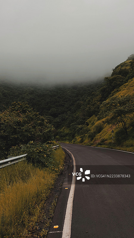 宁静的道路蜿蜒穿过雾气弥漫的森林山丘图片素材