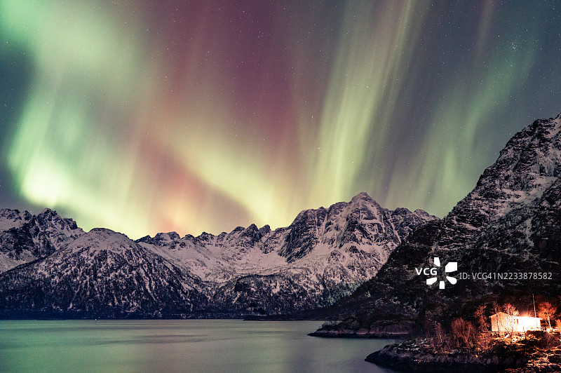 夜晚挪威洛弗敦群岛雪山和湖泊上空的壮丽北极光图片素材