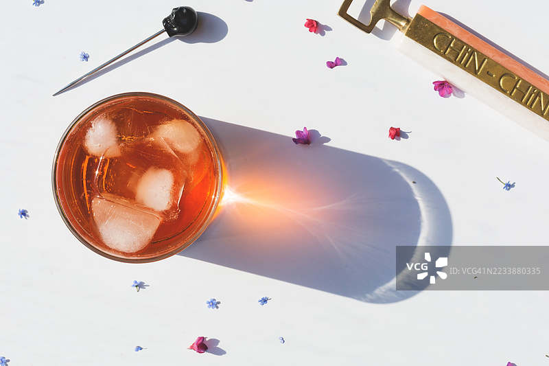 清爽的冰饮料在桌子上投下阴影，周围散落着花朵图片素材