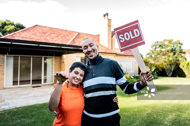 年轻夫妇在院子里展示新房钥匙肖像图片素材