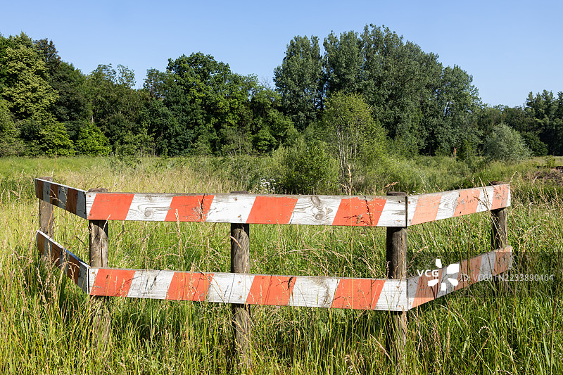 森林中的草地上有红白标记的木栅栏图片素材