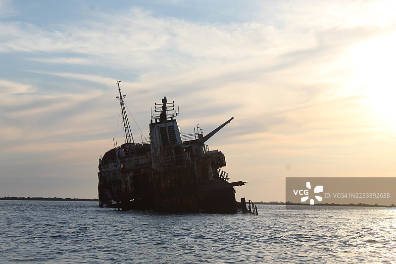 废弃的船只在日落的天空中形成剪影图片素材