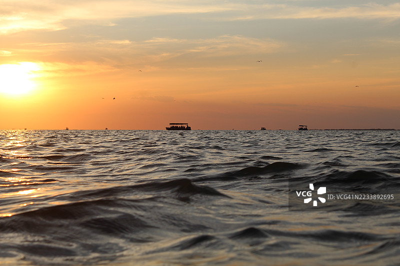 宁静的海洋日落，天边有船只航行图片素材