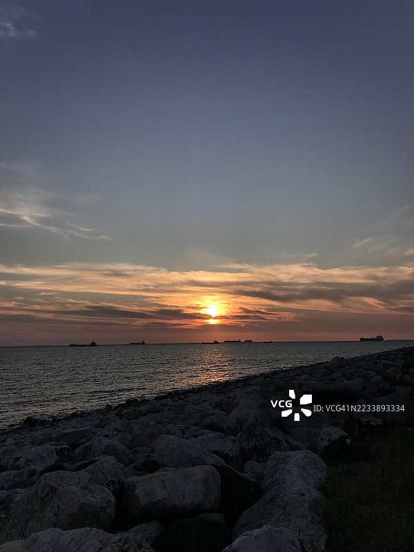 海上日落，远处的船只在地平线上航行图片素材
