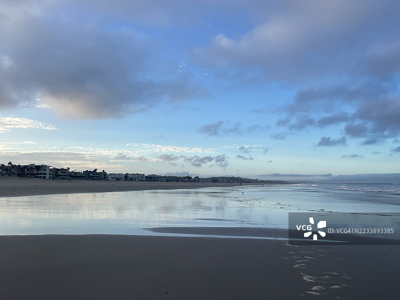宁静的海滩场景，倒映着阴 cloudy 的天空图片素材