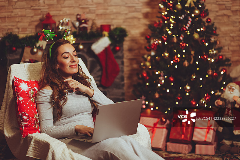 女人在圣诞假期期间使用笔记本电脑和手机图片素材